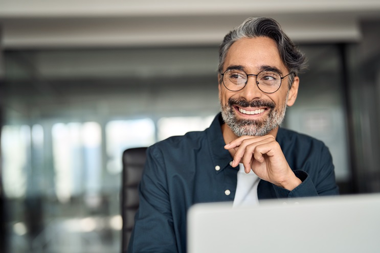 middle aged employee sitting at computer smiling