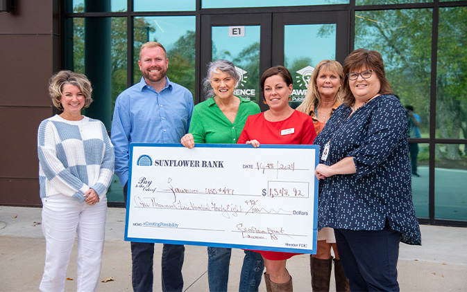 six people holding checks