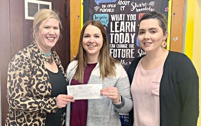 three women holding small check