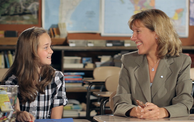 Mollie Carter siting and talking with young female student in classroom